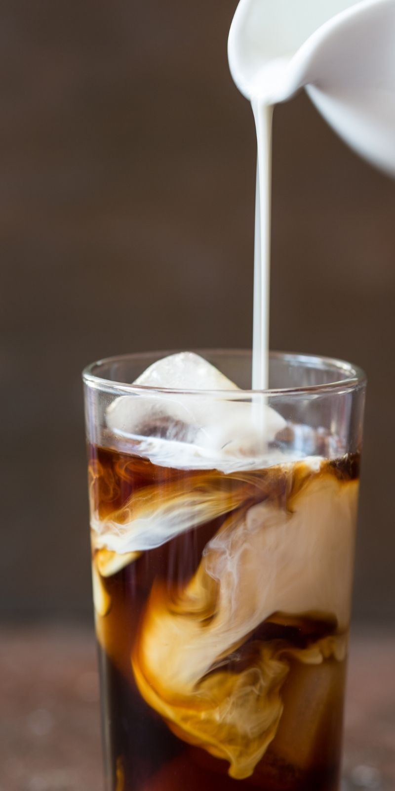 Milk pouring into an iced glass of Angry Kiwi cold brew